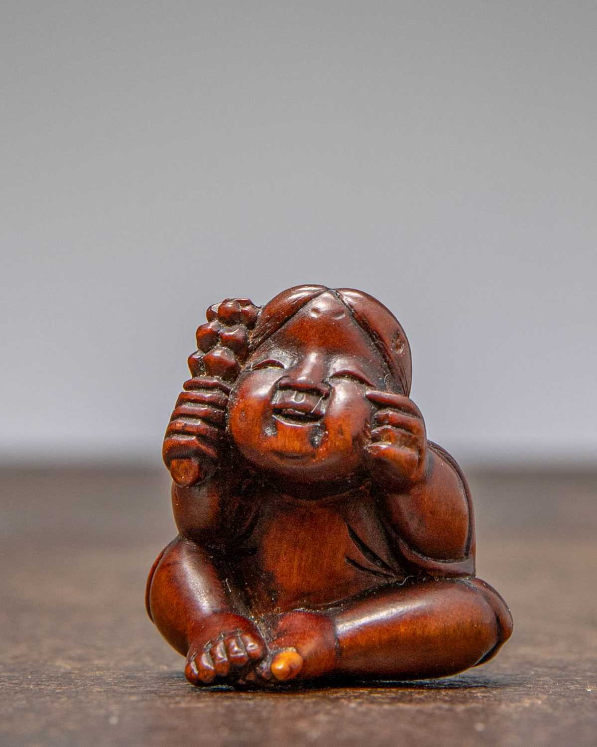 Lot 32 - (R) NETSUKE OF A SEATED CHILD WITH RATTLE