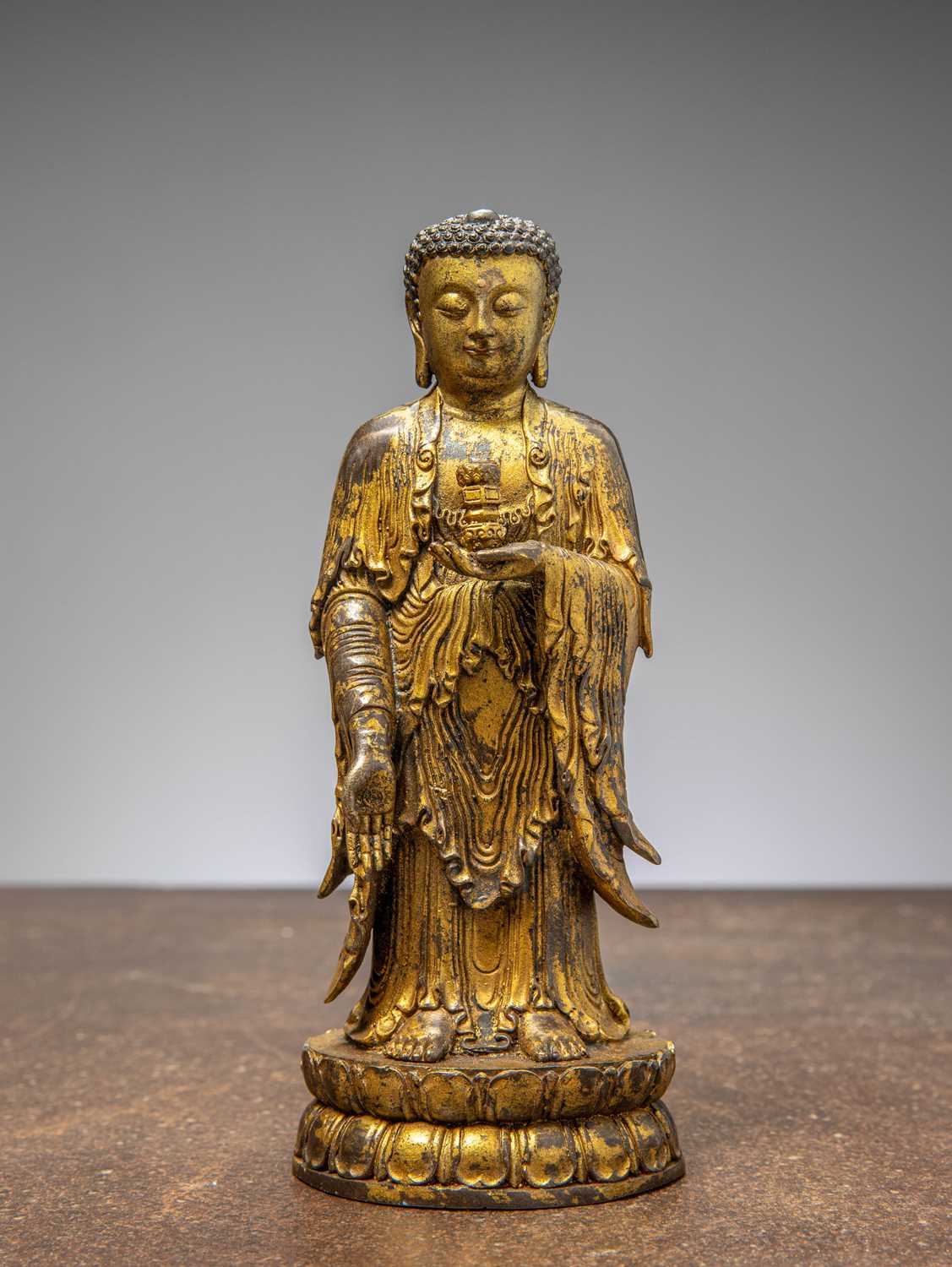 Lot 64 - A GILT-BRONZE BUDDHA HOLDING A VASE, CHINA LATE MINGY DYNASTY