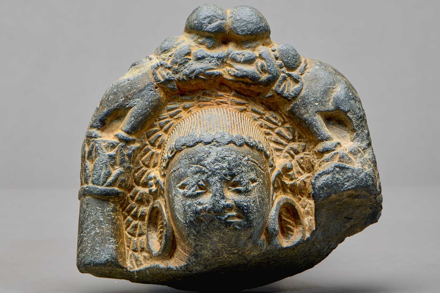 Lot 9 - STONE HEAD OF A BUDDHA WITH ATTENDANT ELEPHANTS, KASHMIR REGION, 4TH–5TH CENTURY